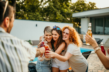 Poolside dancing, a group of friends groove to music near the pool, holding their cocktail bottles and dancing with infectious energy and joy.