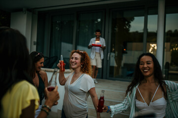 A group of people raise their cocktail bottles, cheering and celebrating the fun moments they've shared throughout the party.