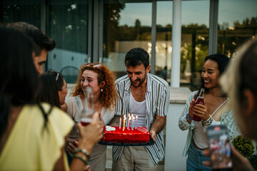 Surprise birthday cake, a group of friends bring out a beautifully decorated birthday cake, surprising one of them.