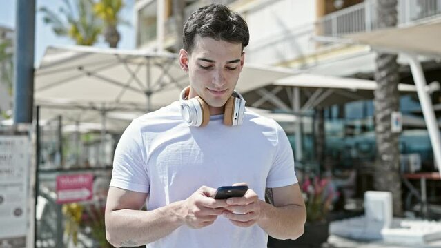 Young hispanic man smiling confident using smartphone at coffee shop terrace