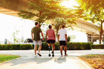 Friend support Friend with a prosthetic leg while exercising outdoor. People walking together on...