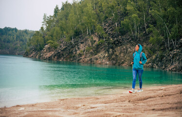 Beautiful woman traveler or tourist with backpack hiking in mountains near lake with beautiful summer landscape on background. Adventure, travel, holiday concept.
