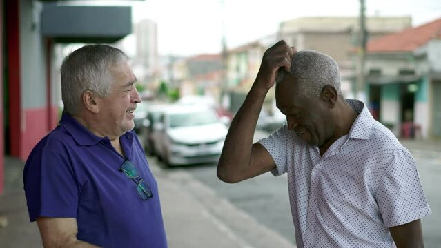 Diverse Elderly People In Candid City Street Conversation, Two Diverse Brazilian Seniors Talking Interaction In Urban Setting