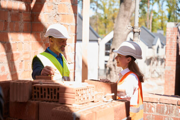 Male contractor talking to female architect near pile of bricks