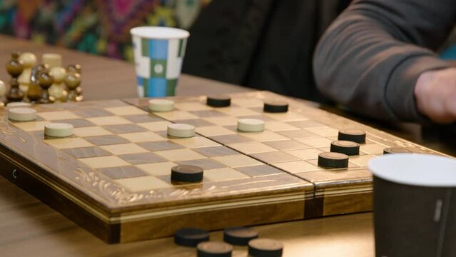 Wooden chessboard during the game. Checkers. The movement of the white checker on the chessboard. Two students play checkers during the break between lessons. strategic thinking concept