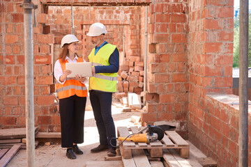 Female architect showing blueprint on laptop to building engineer