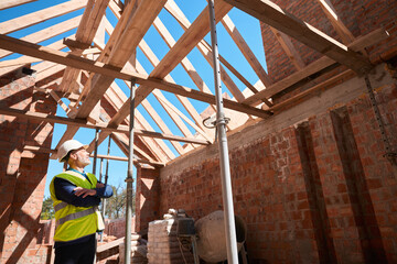 Male constructor in uniform checking walls support and roof beams of building