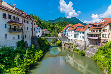 Fototapeta na wymiar A view up the Selca Sora River towards the fourteenth century Capuchin Bridge in the town of Skofja Loka, Slovenia in summertime
