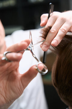 Photo of scissors cutting hair of client indoors