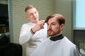 Male hairdresser providing services to his visitor in modern salon