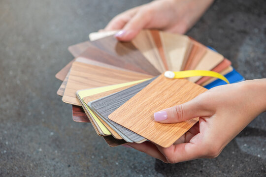 Samples of laminate imitating wood. Woman designer chooses samples of laminate flooring. Floor samples in hands close-up.