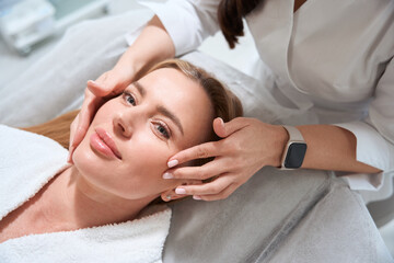Obraz na płótnie Canvas Female masseuse makes a professional facial massage to a patient