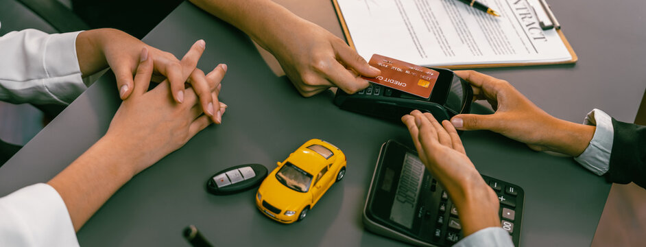 Customer client purchases new car with credit card via electronic terminal after finishing the deal with car dealer. Smooth car ownership transfer with secure electronic digital payment. Prodigy