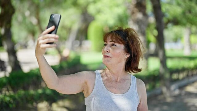 Middle age woman smiling confident making selfie by the smartphone at park