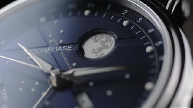 closeup view of rotating luxury swiss watch with moonphase and running second arrow. Macro.