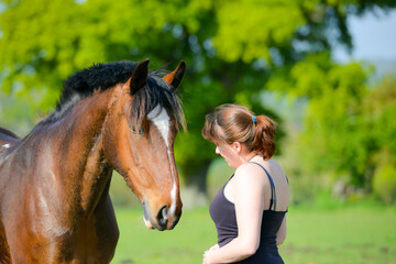 Close up shot of pretty teenage girl and her beautiful bay horse sharing a loving moment in field on summers day in rural Shropshire UK 
