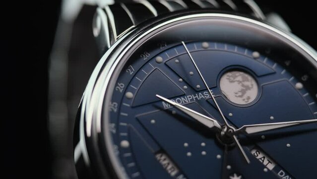 closeup view of rotating luxury swiss watch with moonphase and running second arrow. Macro.