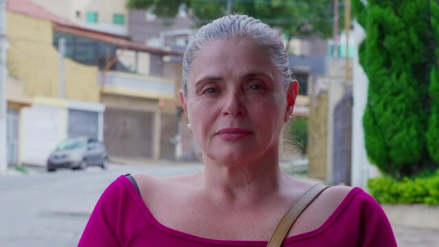 Mature casual woman portrait face standing in street with stern serious expression. 50s female caucasian person