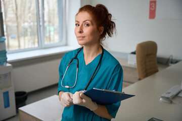 Portrait of female medic holding clipboard in hospital - obrazy, fototapety, plakaty