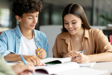 Portrait of school girl and boy studying together, learning language, exam preparation sitting in modern classroom. Back to school, lesson, education concept 