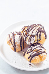 Profiteroles with whipped cream and chocolate filling, vertical, copy space