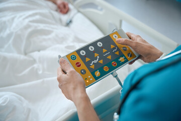 Doctor's hands pressing buttons on supervisor control panel in ward