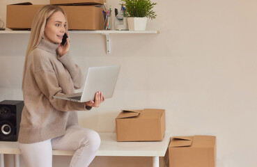 Happy homeowner, renter girl using laptop at pile of stacked boxes, ordering delivery, shipping,...