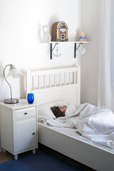 Teenager sleeping in bed at home. Childroom, Lifestyle,relaxing home concept. Boy lies in a bed on a white bedclothes