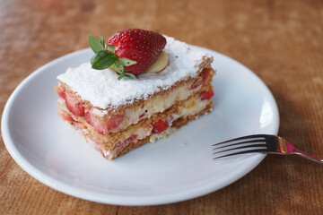 strawberry cream chocolate and cream cake on a plate on table 