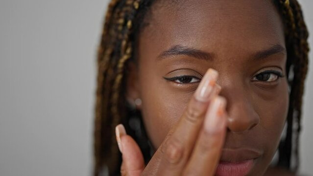 African american woman massaging dark circle over isolated white background