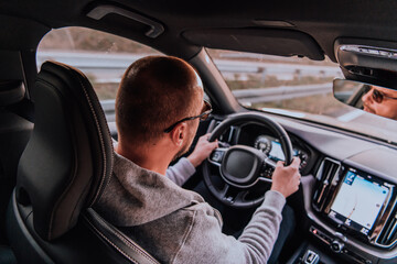 A man with a sunglasses driving a car at sunset. The concept of car travel