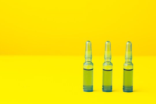 ampollas medicas azules con liquido sobre fondo amarillo