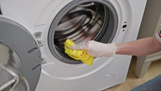 Young blonde woman cleaning washing machine at laundry room