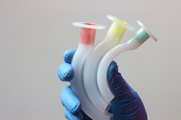 Different sizes of an oropharyngeal airway cannula in a healthcare professional wearing gloves.  - obrazy, fototapety, plakaty