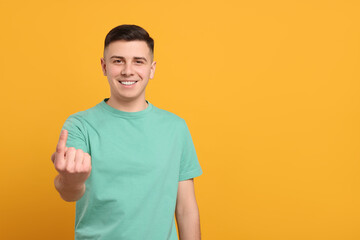 Handsome man inviting to come in against orange background. Space for text