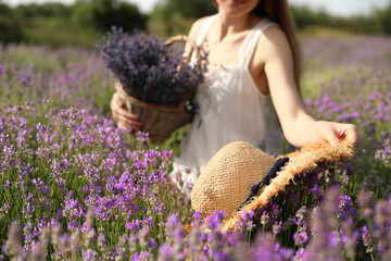 Young woman with straw hat in lavender field on summer day, closeup