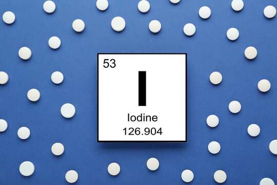 Card with iodine element and pills on blue background, flat lay