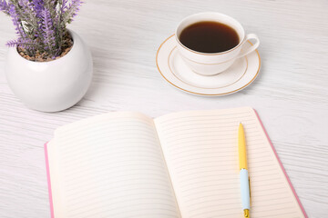 Open planner, pen, cup of coffee and lavender flowers on white wooden table