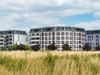Modern residential buildings in the Dresden Mickten district. Facades with balconies are part of the architecture. The property is an investment. A meadow is in the foreground.