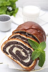 Slices of poppy seed roll and mint on table, closeup. Tasty cake