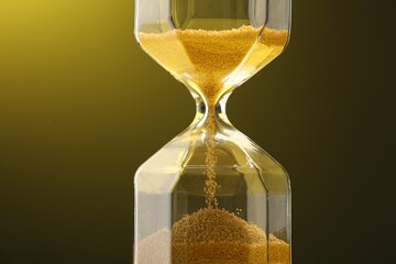 Hourglass with golden flowing sand on color background, closeup
