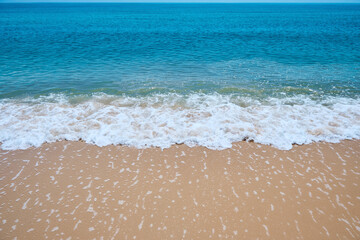 blue sea wave on the yellow sand with white bubbles