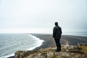 Man looking out at the black sand of Hvalnes Beach