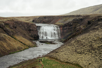 View of the beautiful Thorufoss (&THORN;&oacute;rufoss) waterfall in Iceland with hikers walking to falls.