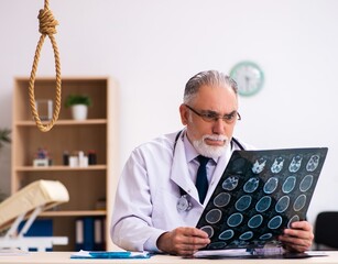 Old male doctor committing suicide at workplace