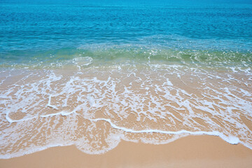 Fototapeta na wymiar blue sea wave on the yellow sand with white bubbles