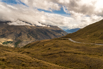 Obraz premium Looking down from the top of the Crown Range road over the agricultural land in the Queenstown valley with the town in the distance