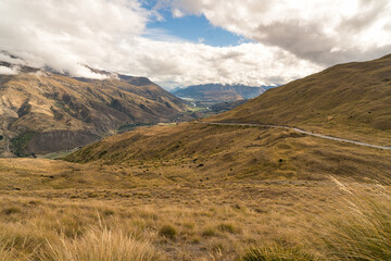 Fototapeta premium Looking down from the top of the Crown Range road over the agricultural land in the Queenstown valley with the town in the distance