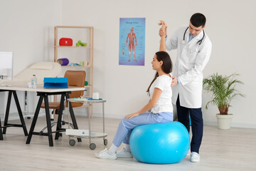 Male doctor checking posture of young woman in clinic