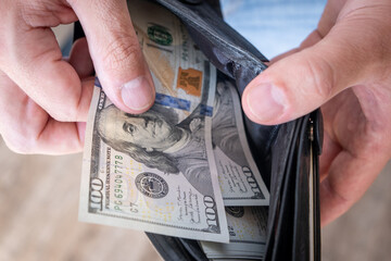 A man in a white shirt holds a wallet with money, counts it and offers it to another. Close up male...